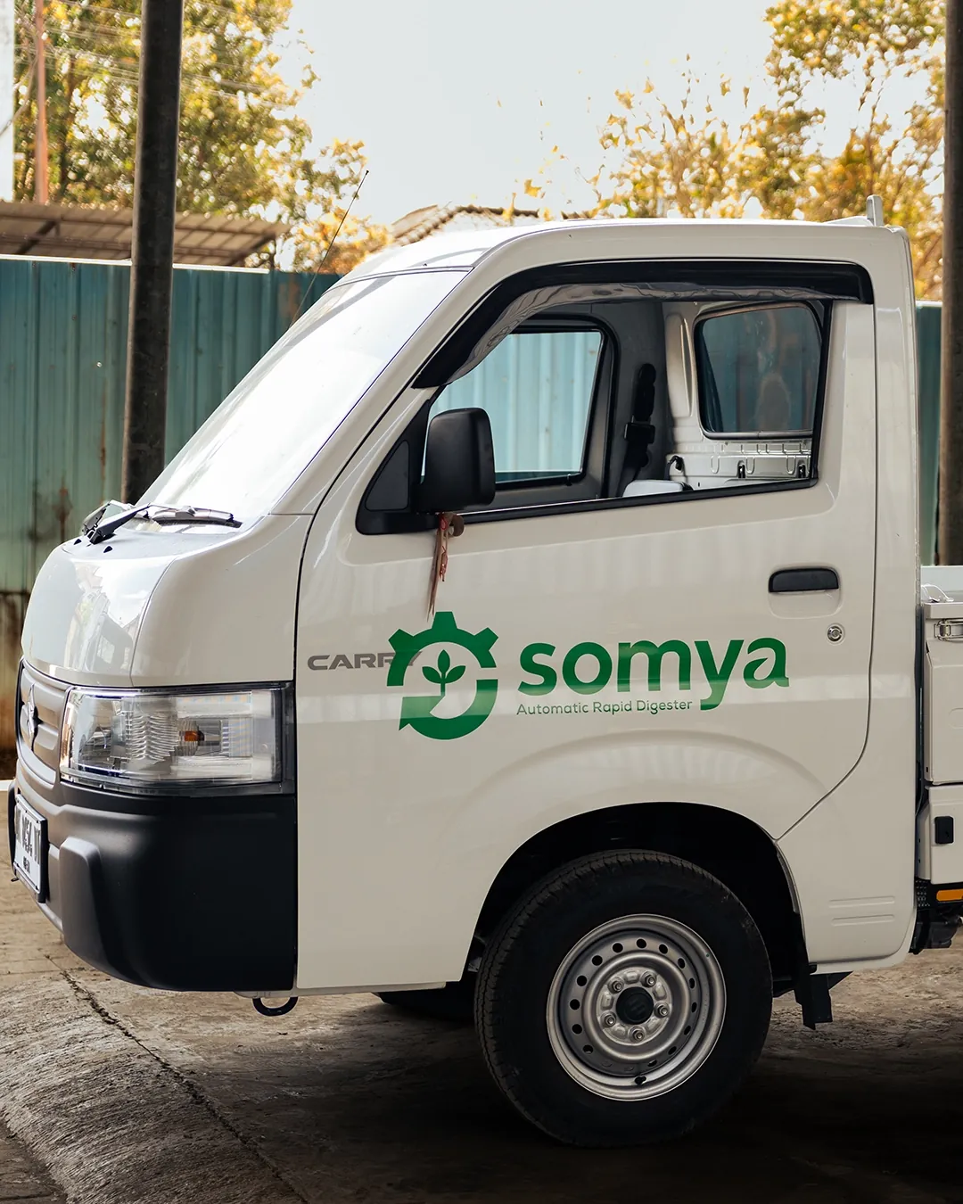 Mobil pikap putih SOMYA dengan logo hijau untuk pengangkutan sampah organik